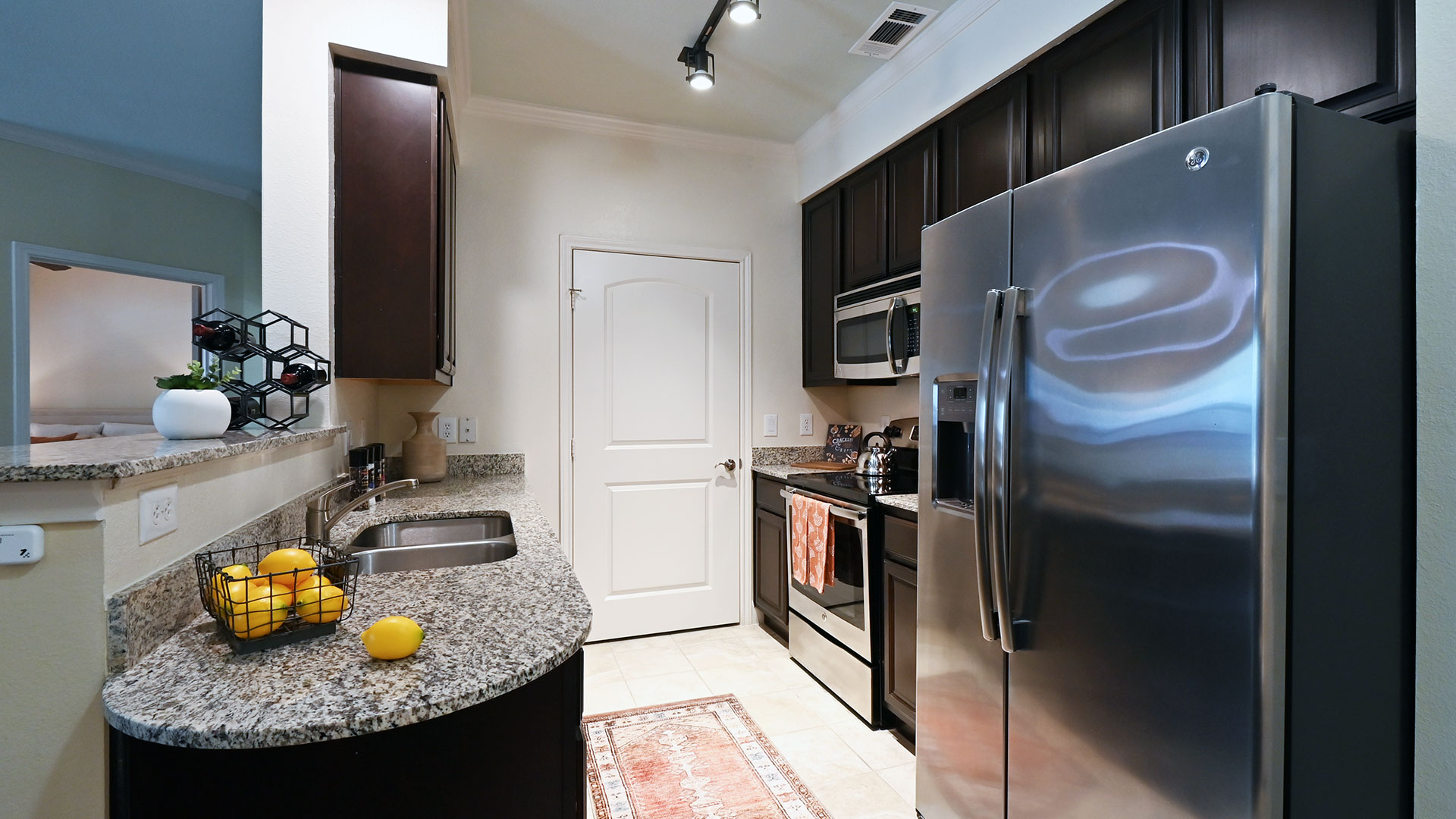 A galley kitchen with stainless appliances on the right and a counter with sink on the left.